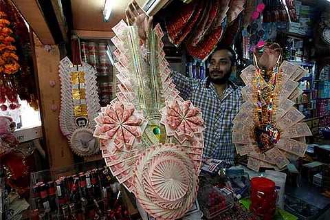A shopkeeper displays garlands made of notes at a market in Chandigarh