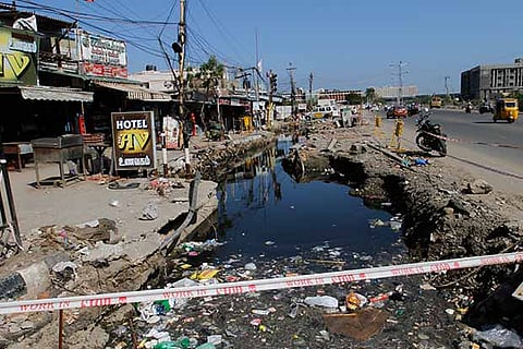 A large ditch filled with stagnant water and waste material on Taramani Link Road
