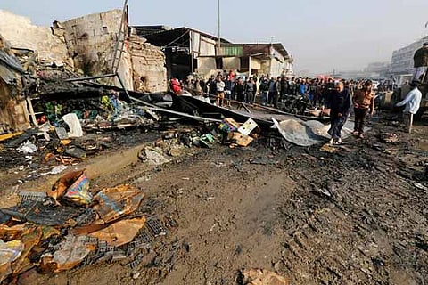 People gather at the site of a car bomb attack at a vegetable market in eastern Baghdad