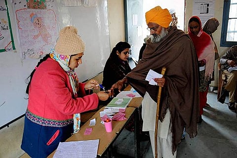 A voter is being applied the indelible ink after casting his vote at a polling booth near Amritsar