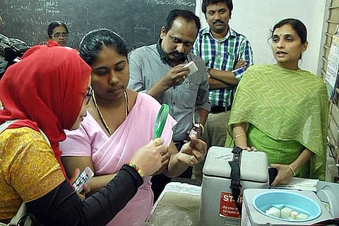 WHO representative examines the vaccine in Salem