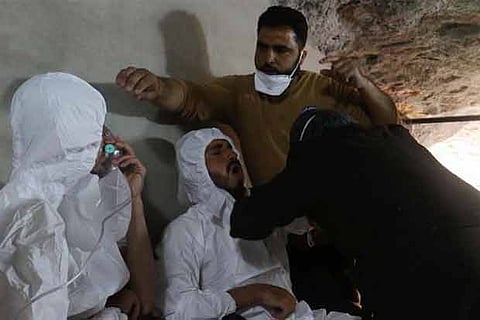 A man breathes through an oxygen mask as another one receives treatments in Syria