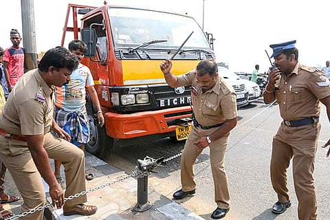 Police trying to break a chain that was tied across the Kathipara grade separator by protesters