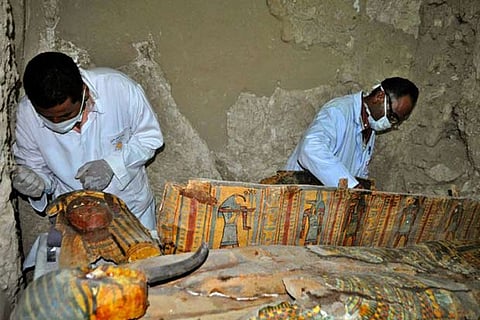 Members of an Egyptian archaeological team work on a wooden coffin