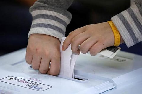 A woman wearing a wristband in remembrance of the Sewol ferry disaster casts her vote