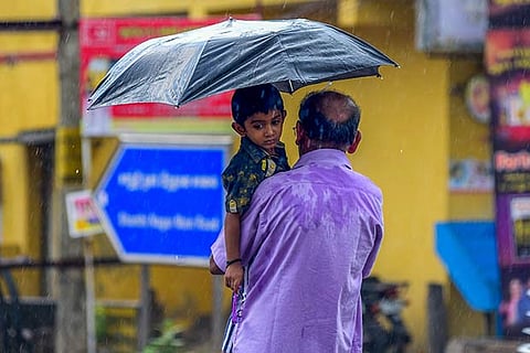 A man carrying a child under cover of umbrella during a brief spell of rain in the city