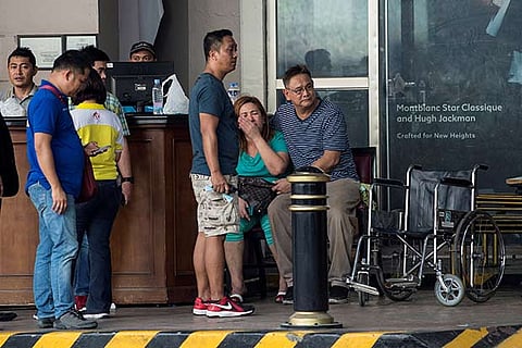 Relatives of a victim sit in front of the Resorts World Hotel following an assault in Manila