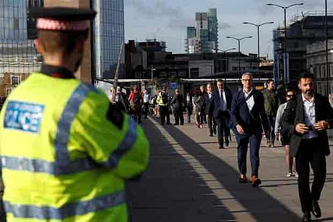 Commuters walk past a City of London police officer standing on London Bridge.(Reuters)
