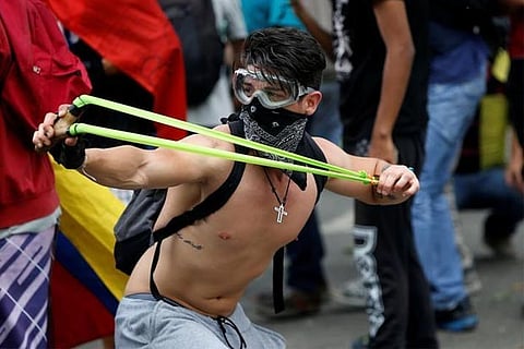A demonstrator uses a sling shot while clashing with riot security during a rally