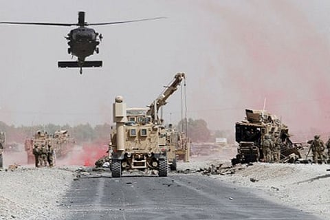 US troops assess the damage to an armoured vehicle of NATO-led military coalition