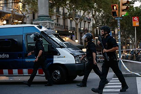 Spanish policemen walk in a cordoned off area after a van ploughed into the crowd, killing 13