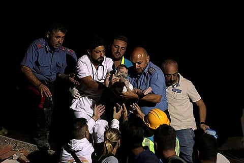 Italian police and a doctor carry a child after an earthquake hit the island of Ischia
