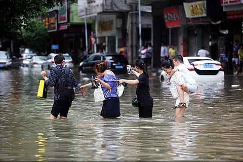 People walk through a flooded street as Typhoon Hato hits Dongguan, Guangdong province, China
