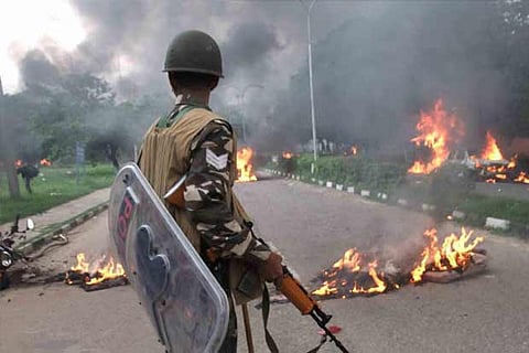 Security personnel at Panchkula looks at vehicles burning in violence following Dera chief Gurmeet