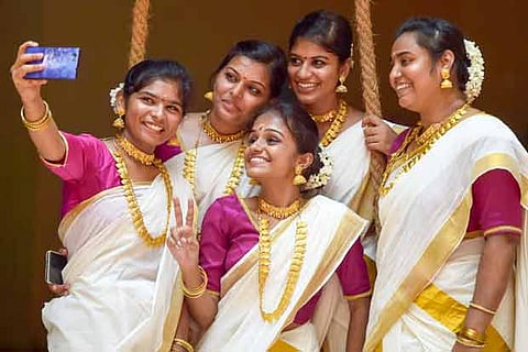 Girls wearing traditional attire take selfies during Onam celebrations. Photo: Manivasagan N