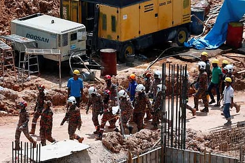 Rescue workers carry the body of a landslide victim at a construction site in Tanjung Bungah, Penang