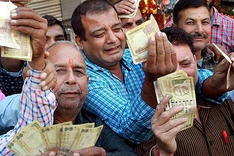 People showing demonetized 500 and 1000 rupees notes