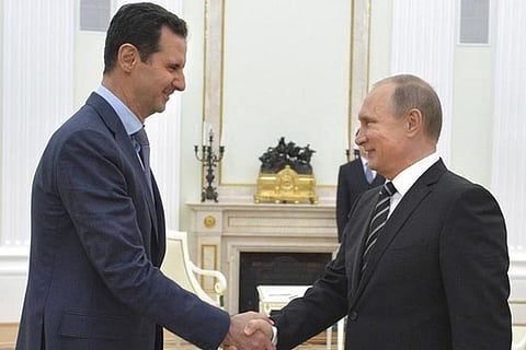 Russian President Vladimir Putin (R) shakes hands with Syrian President Bashar al-Assad