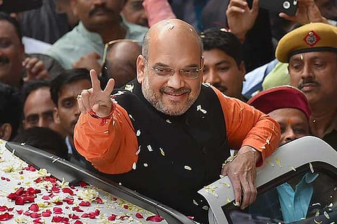 BJP Prez Amit Shah gestures while being welcomed on his arrival at the party hq in New Delhi
