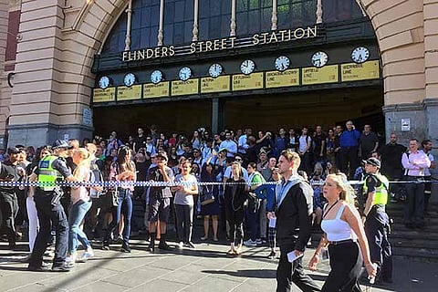 Public stand behind police tape near the Flinders Street train station in central Melbourne