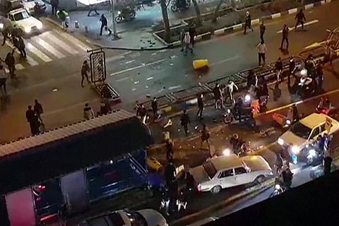 A group of men pulling at a fence in a street in Tehran