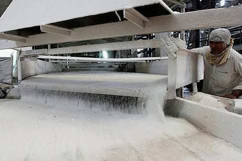 A worker checks the flow of sugar inside a sugar factory