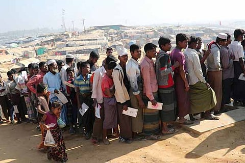 Rohingya refugees stand in a queue to collect aid supplies in Cox's Bazar, Bangladesh