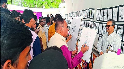 डॉ. अतुल कापडी यांचे चित्र काढून दाखविताना चित्रकार रामकृष्ण कांबळे तर बाजूला व्यंगचित्र काढून दाखविताना प्रभाकर वाइरकर.