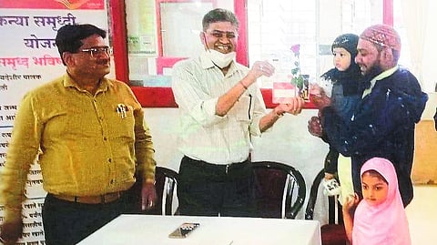 Senior Officer Mohan Aherrao, Ramsingh Pardeshi while giving passbook to the beneficiary of Sukanya Yojana.