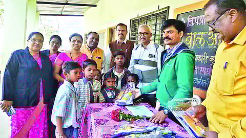 Group Education Officer Nilesh Patil giving school materials to migrant students at the brick kiln here