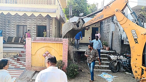 A team of JCB demolishing the wall compound of a house on encroached land in Sakri Road area