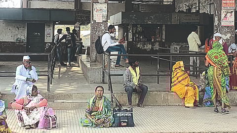 Passengers sitting at the station waiting for the bus.