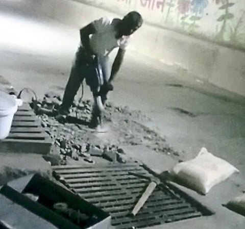 Workers working on filling potholes in railway subway.