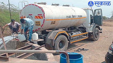 Workers pouring water from a tanker into a well acquired to supply water to the village.
