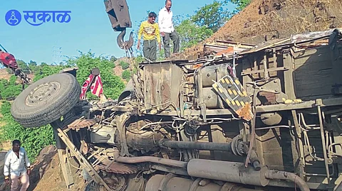 Disaster team and highway security police team extricating the driver and assistant trapped under the overturned truck in the ghat