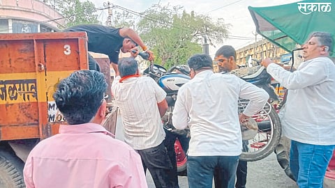 Jalgaon: Muncipal employee putting the bike parked on the road into the tractor.
