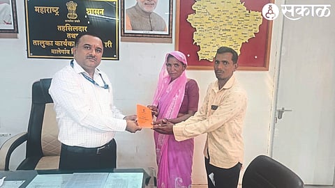 Tehsildar Nitin Kumar Deore giving immediate ration card to Anusayabai Sonwane of Dabhadi.