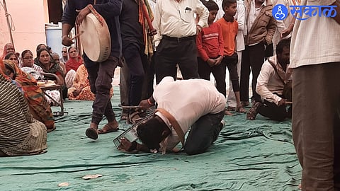 While playing the tambourine, holar while picking up money note on ground with eyelids.