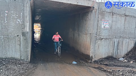 A student on a bicycle wading through standing water in an underpass.