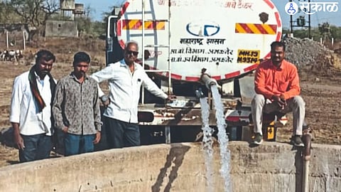 Workers pouring water into well with help of a tanker.