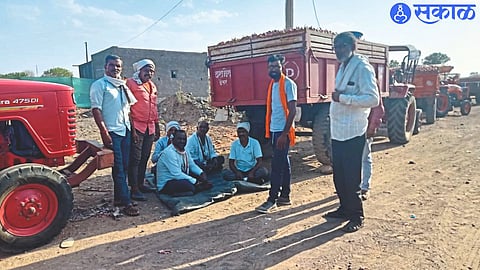 Farmers sitting in the shadow of the vehicles that brought onion for sale as there is no water and shade facility for the farmers in the onion market.