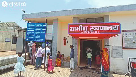 Patients and their relatives standing in the sun during the afternoon session to collect case papers in a rural hospital.