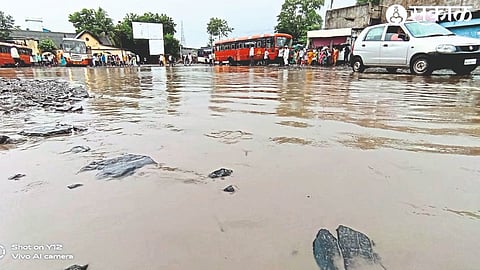 Commuters wading through rainwater that has accumulated in the bus station premises.