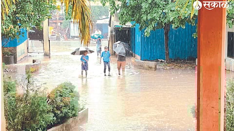 Students wade through rainwater in the Municipal High School premises.