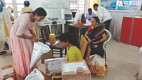 Postal department staff inspecting and packing before sending Diwali snacks abroad.