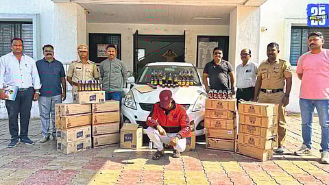 Police officials displaying seized liquor bottles and the car used in smuggling.