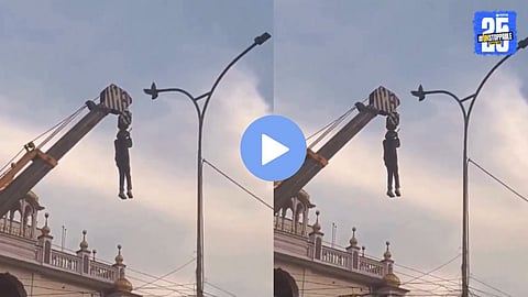 A man using a crane to rescue a pigeon trapped in ropes on a streetlight pole, showcasing humanity and compassion.