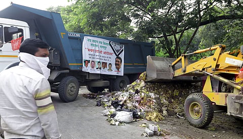 ट्रकमध्ये कचरा टाकताना कार्यकर्ता.