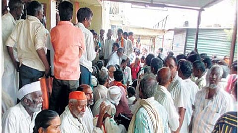 Senior citizens waiting outside the tehsil gate as server issues cause delays in services, leaving them hungry and frustrated."