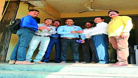 उशीरा आलेल्या कर्मचार्यांना गुलाब पुष्प देताना अधिकारी.